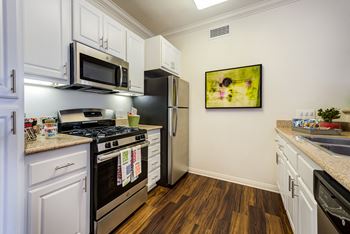 a kitchen with white cabinetry and stainless steel appliances at Barrington Place, Rancho Cucamonga, California